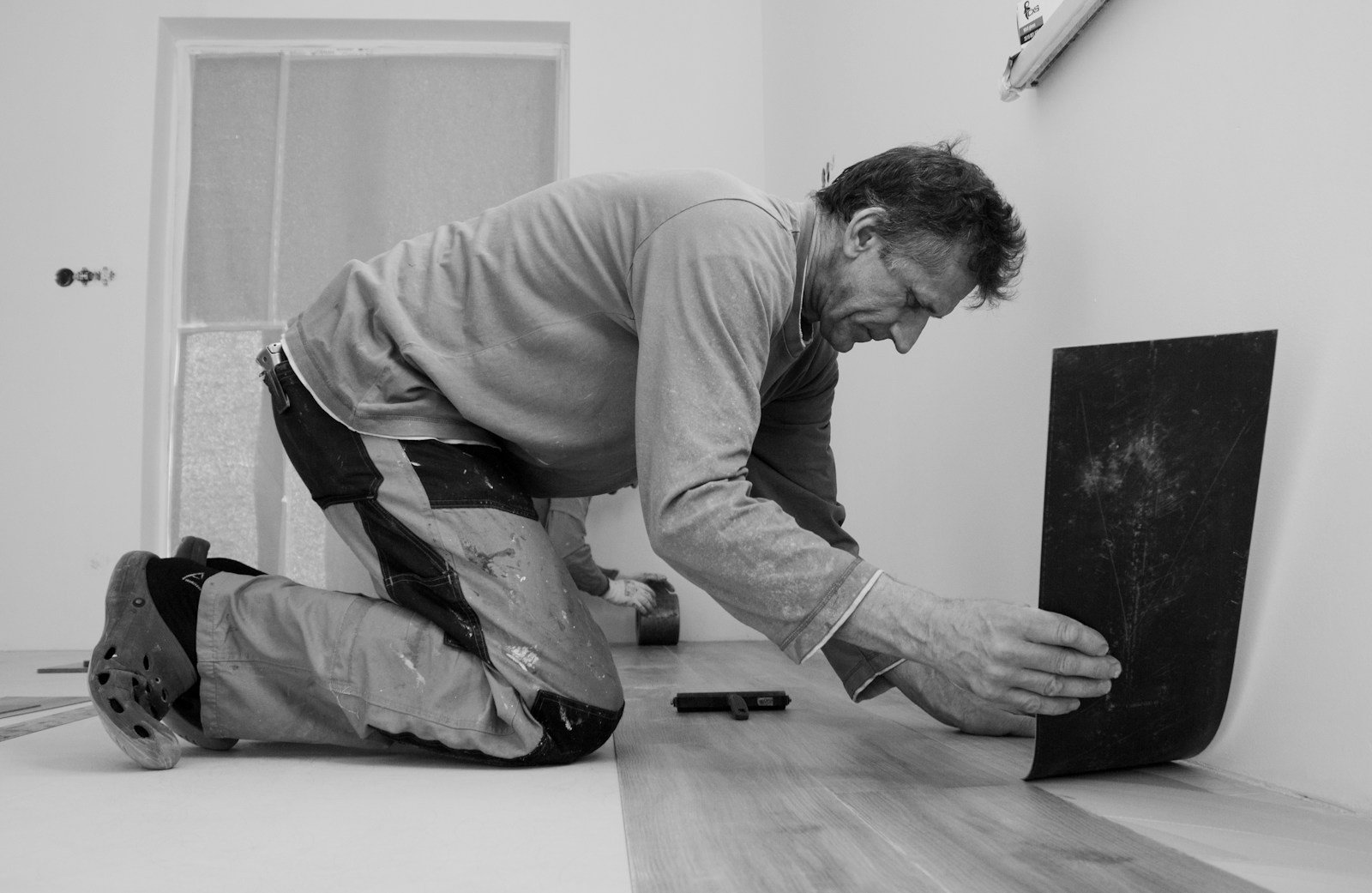 Artisan posant des panneaux de plancher en aggloméré sur des solives en bois
