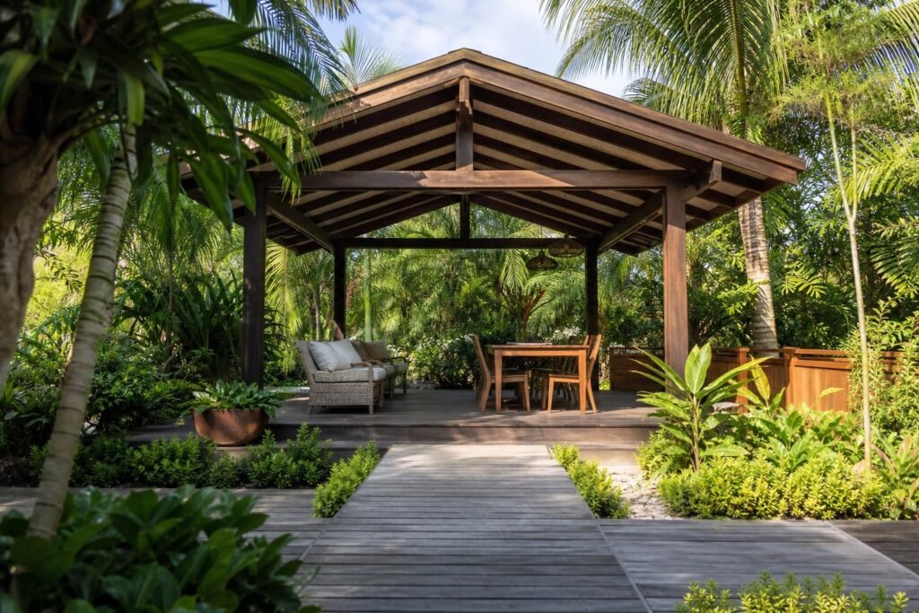 Carbet en bois ouvert au fond d'un jardin tropical, structure d'ombre indépendante de la maison