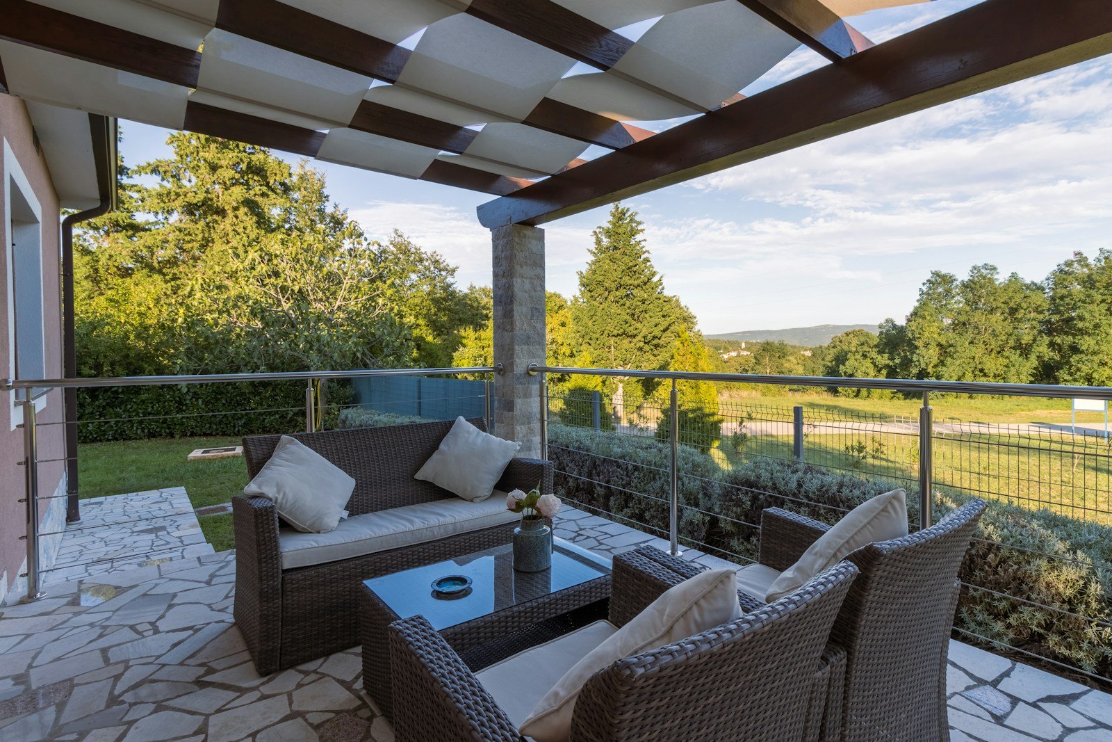Coin salon en rotin installé sous une terrasse couverte, protégé du soleil direct