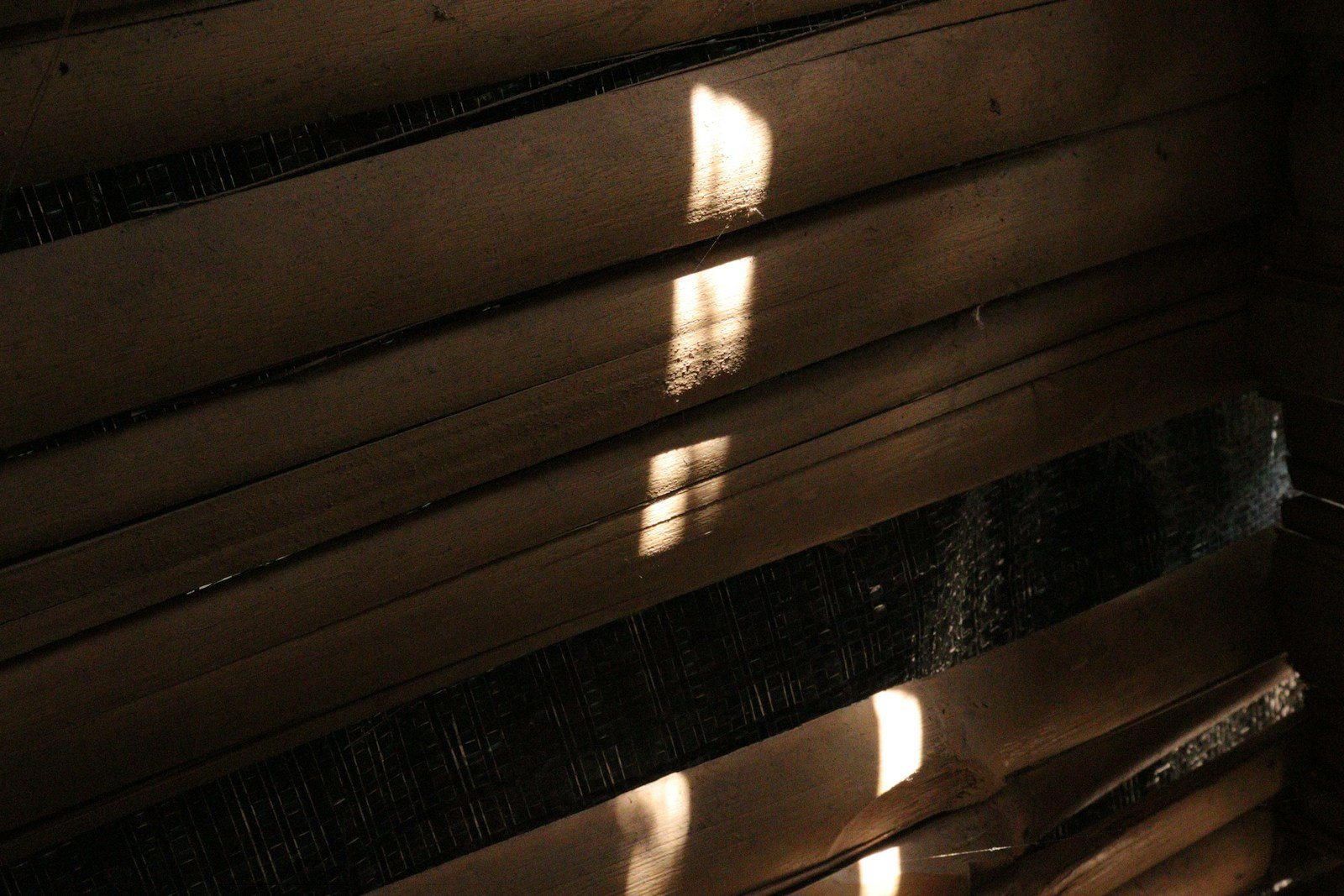Intérieur d'une maison créole aux volets en bois entrouverts, lumière filtrée
